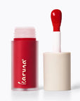 Red lipstick with applicator on a white background, featuring the brand 'karuna'.