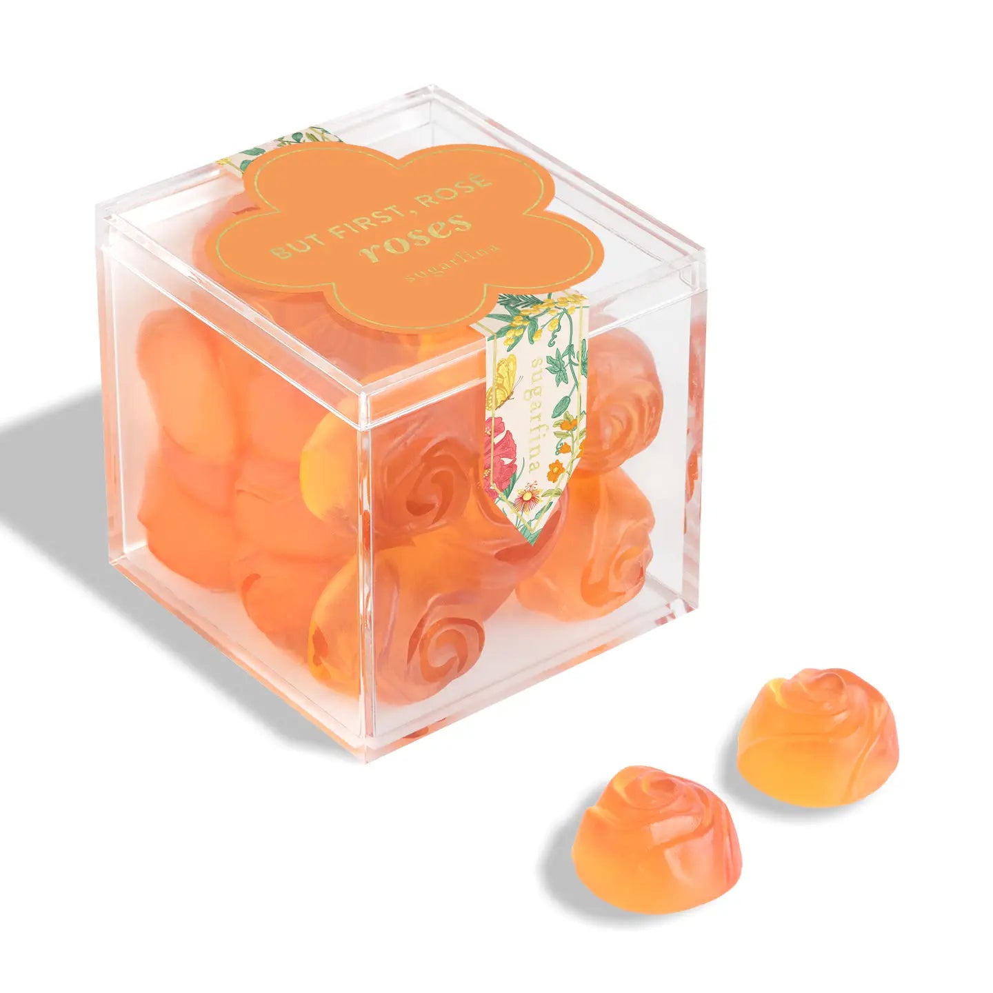 Clear cube box with orange rose-shaped candies on a white background