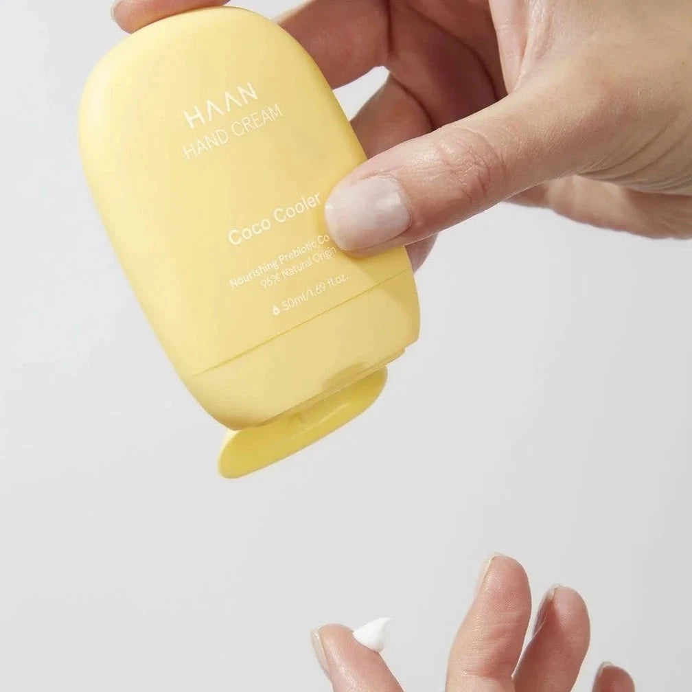 hand holding yellow cream container putting lotion on finger tip