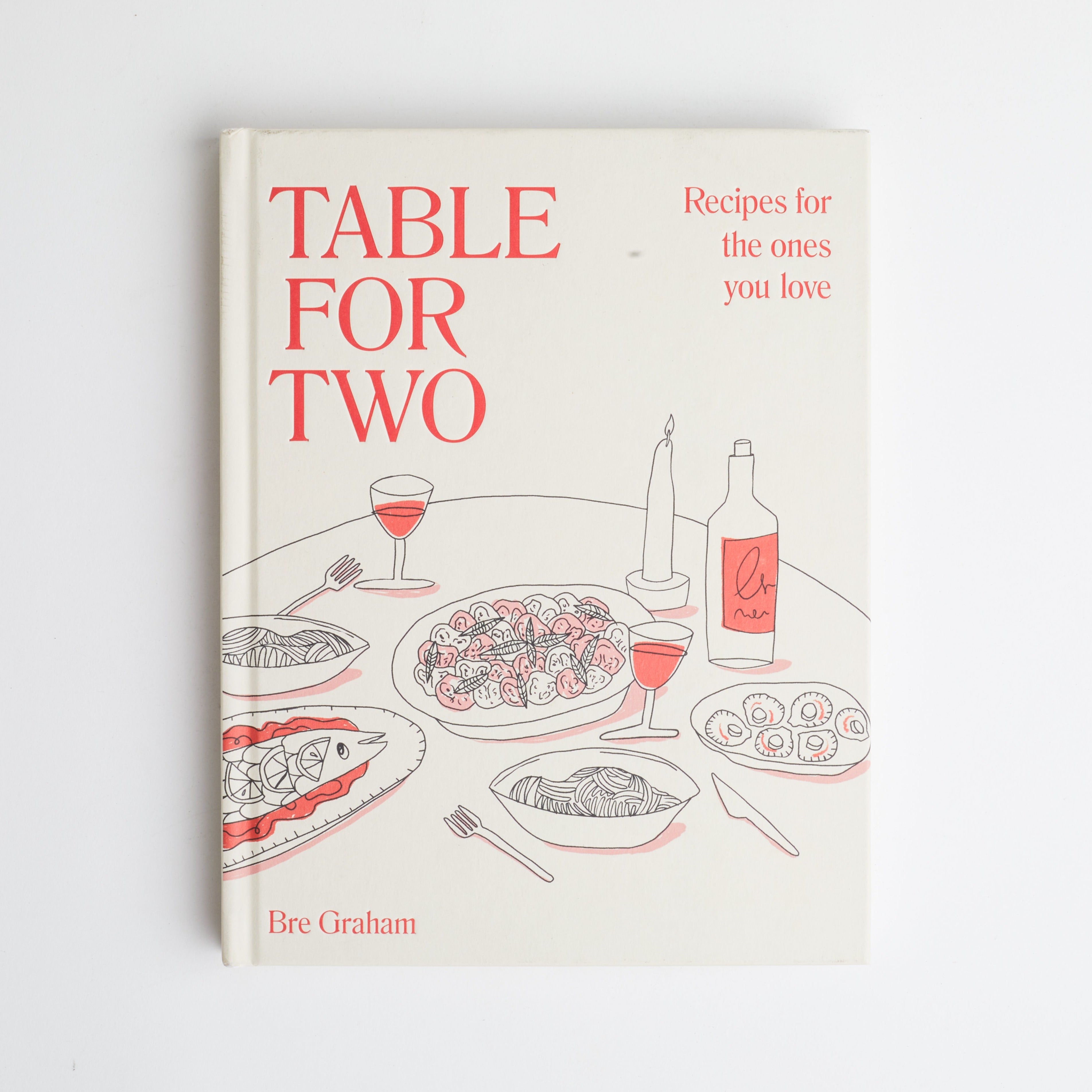 Book cover that reads table for two with red font and graphic of food on table