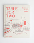 Book cover that reads table for two with red font and graphic of food on table