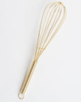 An 8" gold metal whisk against a white background
