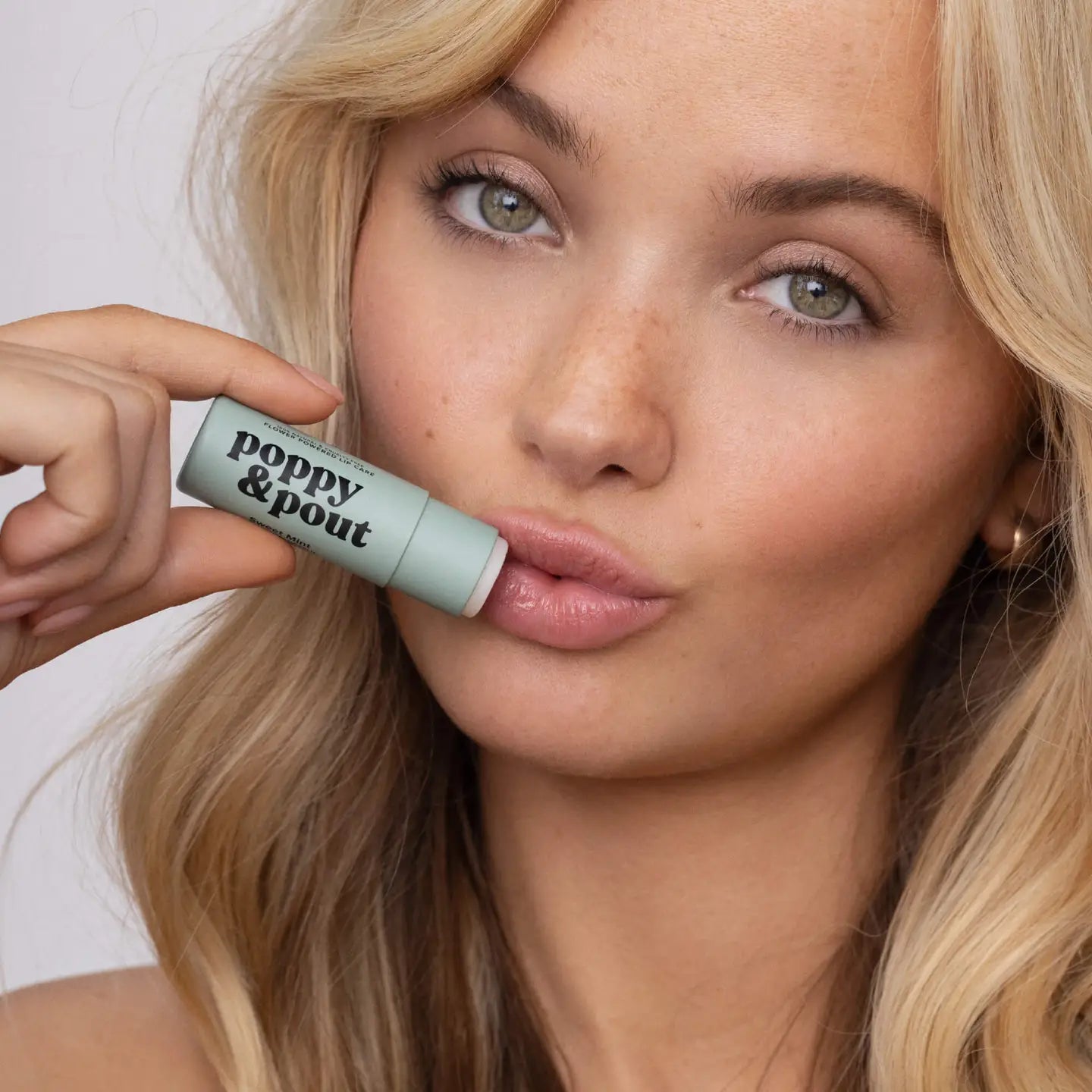 woman holding the poppy &amp; pout lip balm