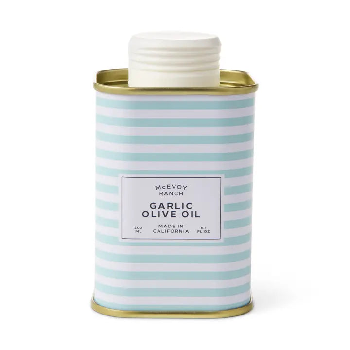 McEvoy Ranch Garlic Olive Oil in a square metal tin with a white screw cap, featuring a light blue and white striped pattern with a white label and gold-toned metal rims.