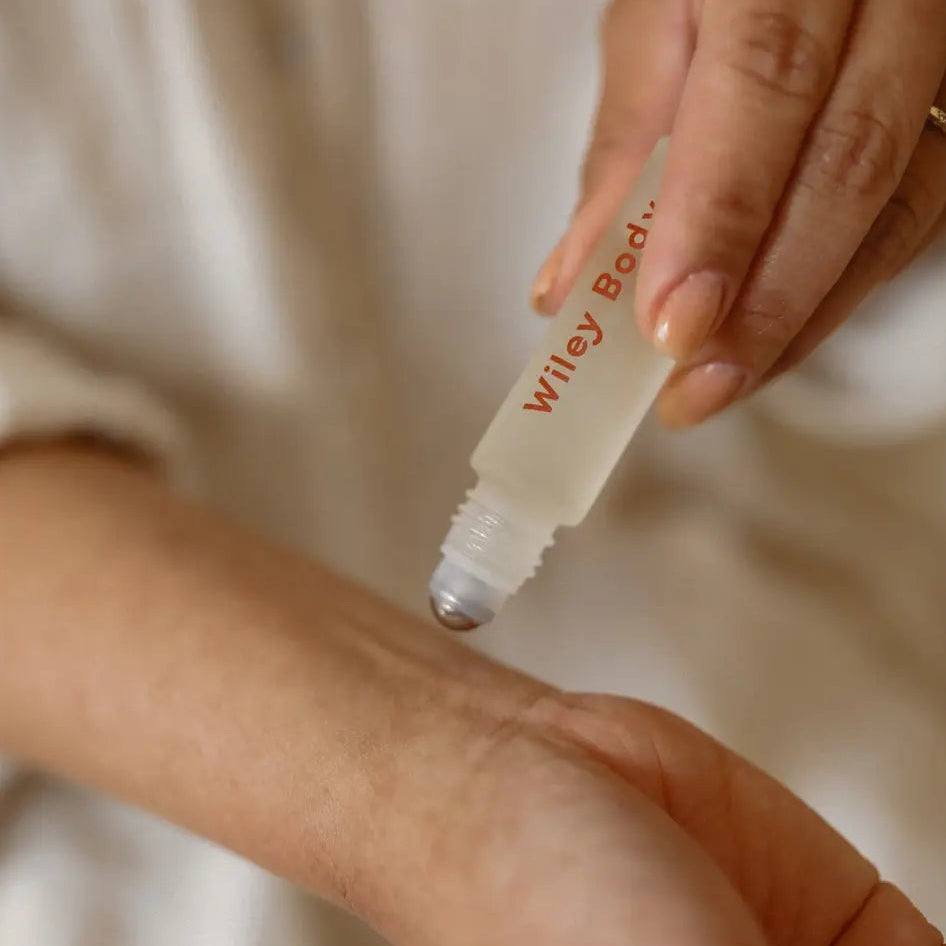 Person applying Wiley Body product to their arm with a roller bottle.