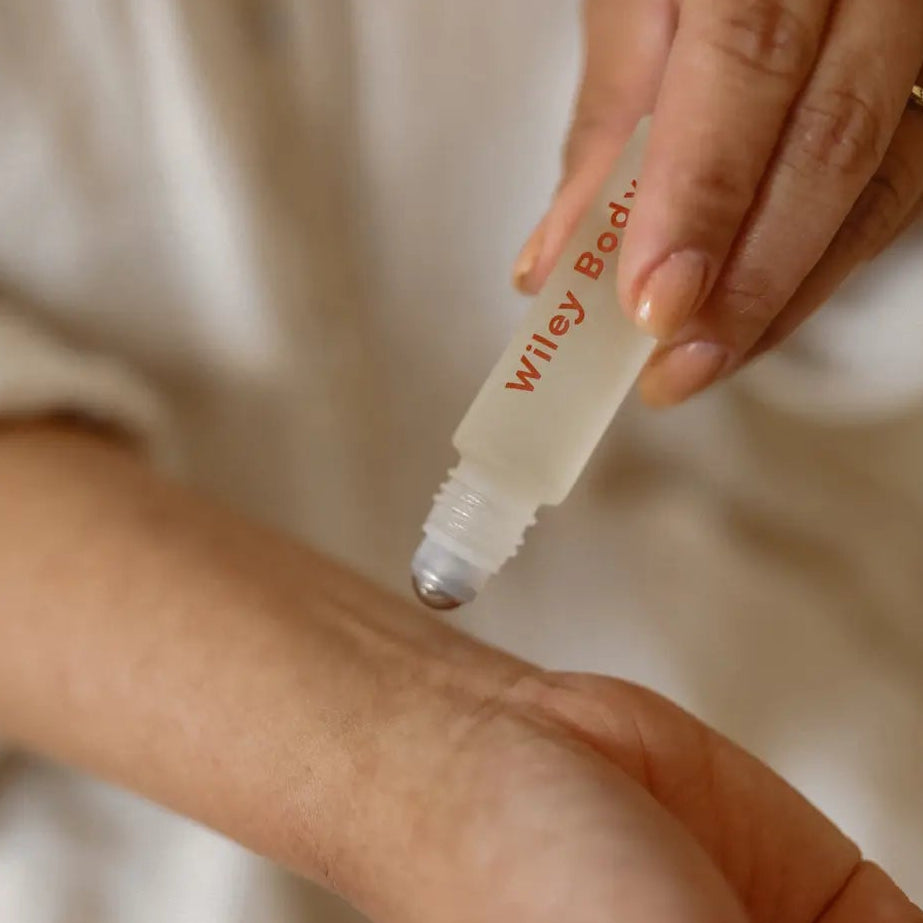 Person applying Wiley Body product to their arm with a roller bottle.
