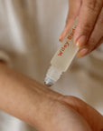 Person applying Wiley Body product to their arm with a roller bottle.