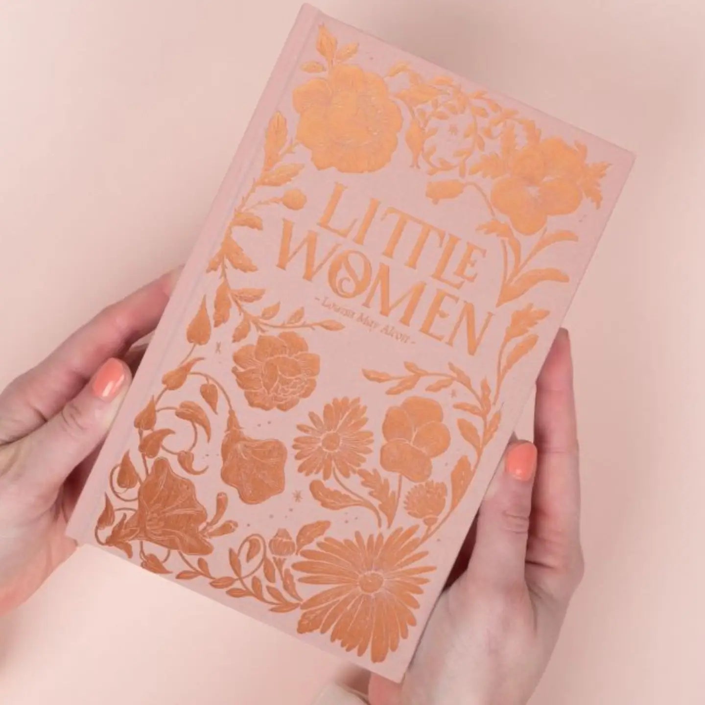 Book titled 'Little Women' with floral design on a pink background