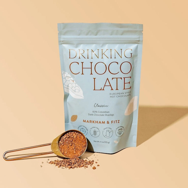 Packaging of 'Drinking Chocolate' with a scoop of powder on a beige background