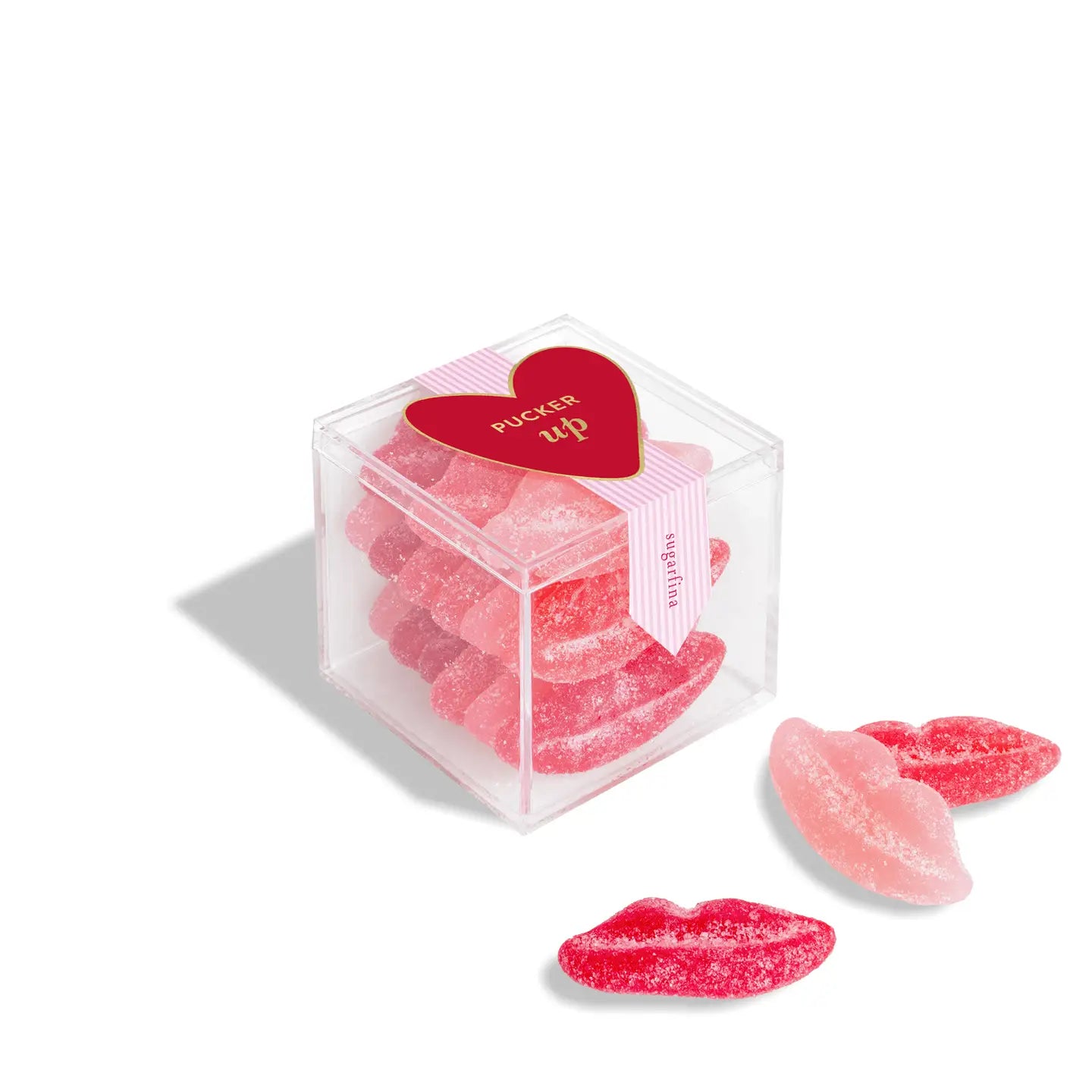 Pink candy shaped like lips in a clear cube with a heart-shaped label on a white background