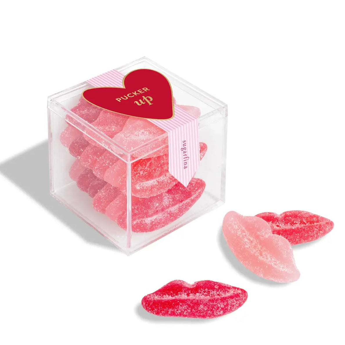 Pink candy shaped like lips in a clear cube with a heart-shaped label on a white background