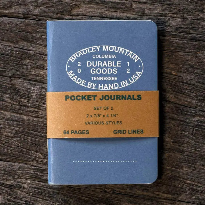 Blue pocket journal with brown band and 'Bradley Mountain' branding on a wooden surface