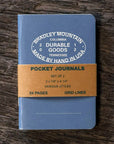 Blue pocket journal with brown band and 'Bradley Mountain' branding on a wooden surface