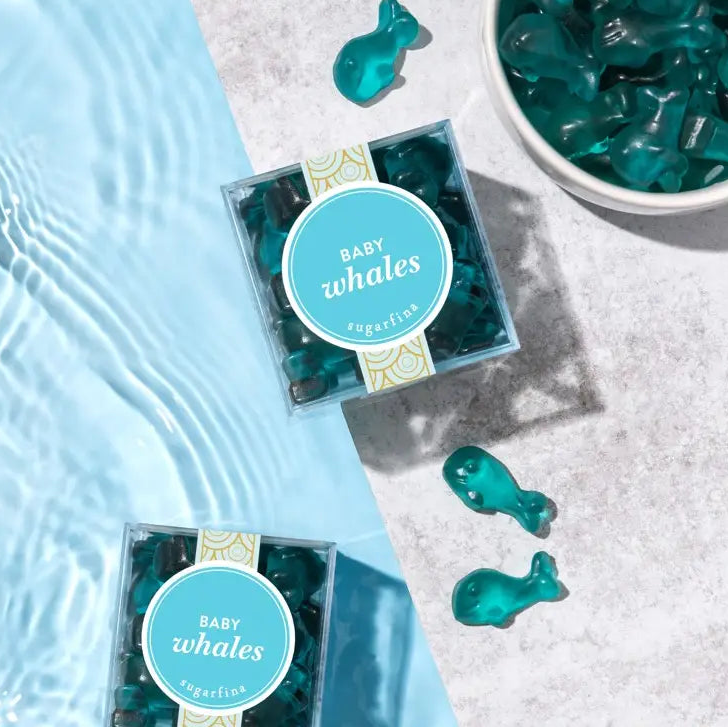Blue whale-shaped gummy candies in clear packaging on a light blue and gray surface.
