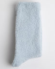 folded light blue fuzzy socks. material is fluffy and cozy, suggesting it could provide warmth or comfort. It is laid flat against a plain white background.






