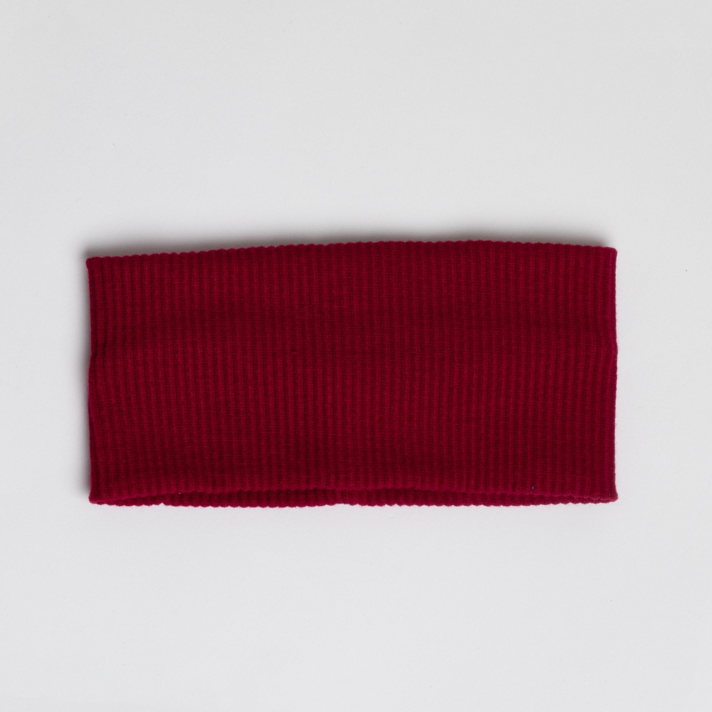 This is an image of a red ribbed fabric headband or neck warmer, laid flat on a plain white background.