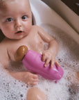 Baby in a bathtub with bubbles holding a purple toy