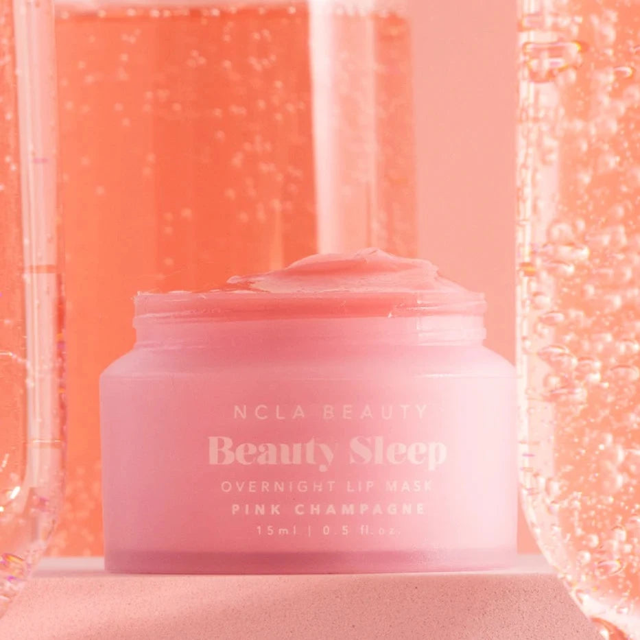 Pink Champagne Beauty Sleep Overnight Lip Mask pot surrounded by sparkling pink champagne in flutes