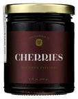Jar of bourbon infused cherries with a maroon label on a white background