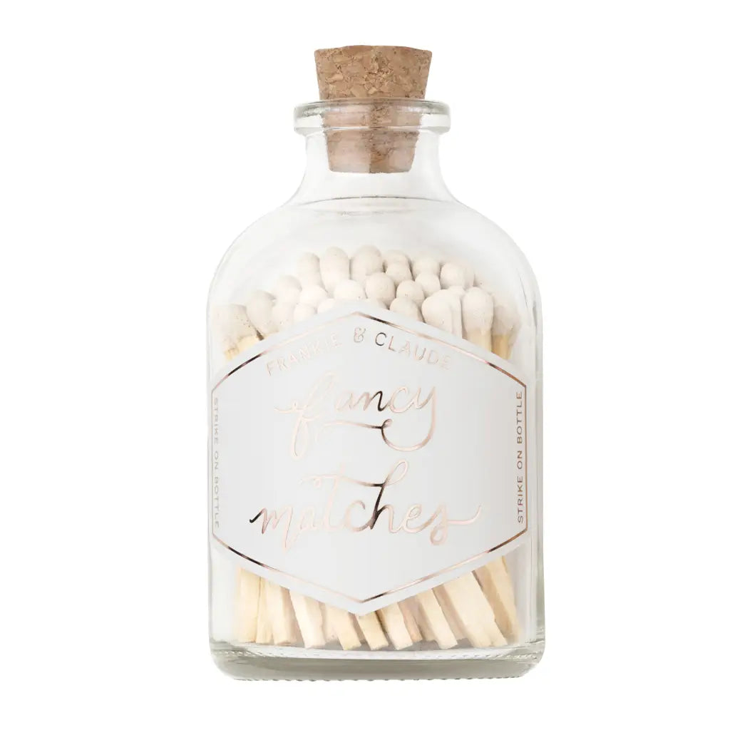 Glass bottle with cork lid containing matches on a white background