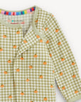 Green checkered baby outfit with orange pumpkin patterns on a white background