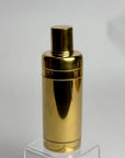Gold metallic cocktail shaker on a clear stand with a white background