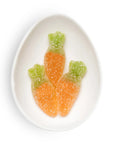 Three carrot-shaped gummy candies on a white plate with a white background