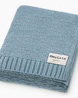 Folded blue knit blanket with 'Bleu La La Organics' label on a white background