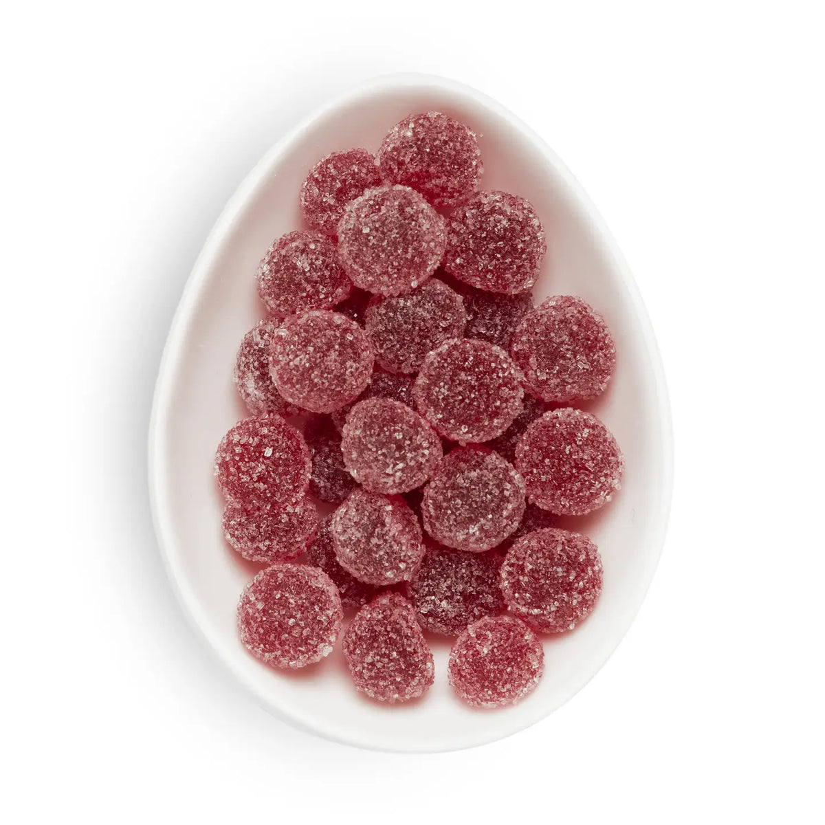 Red sugar-coated gummy candies piled in an oval white dish on a white background.
