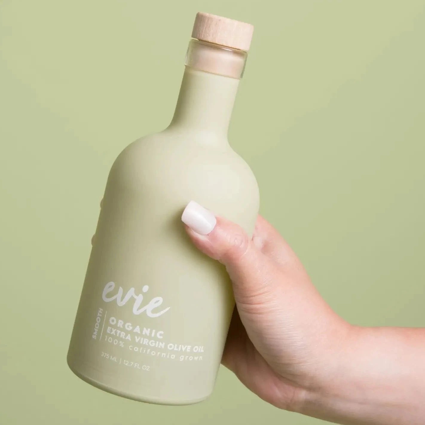 hand holding sage green olive oil bottle