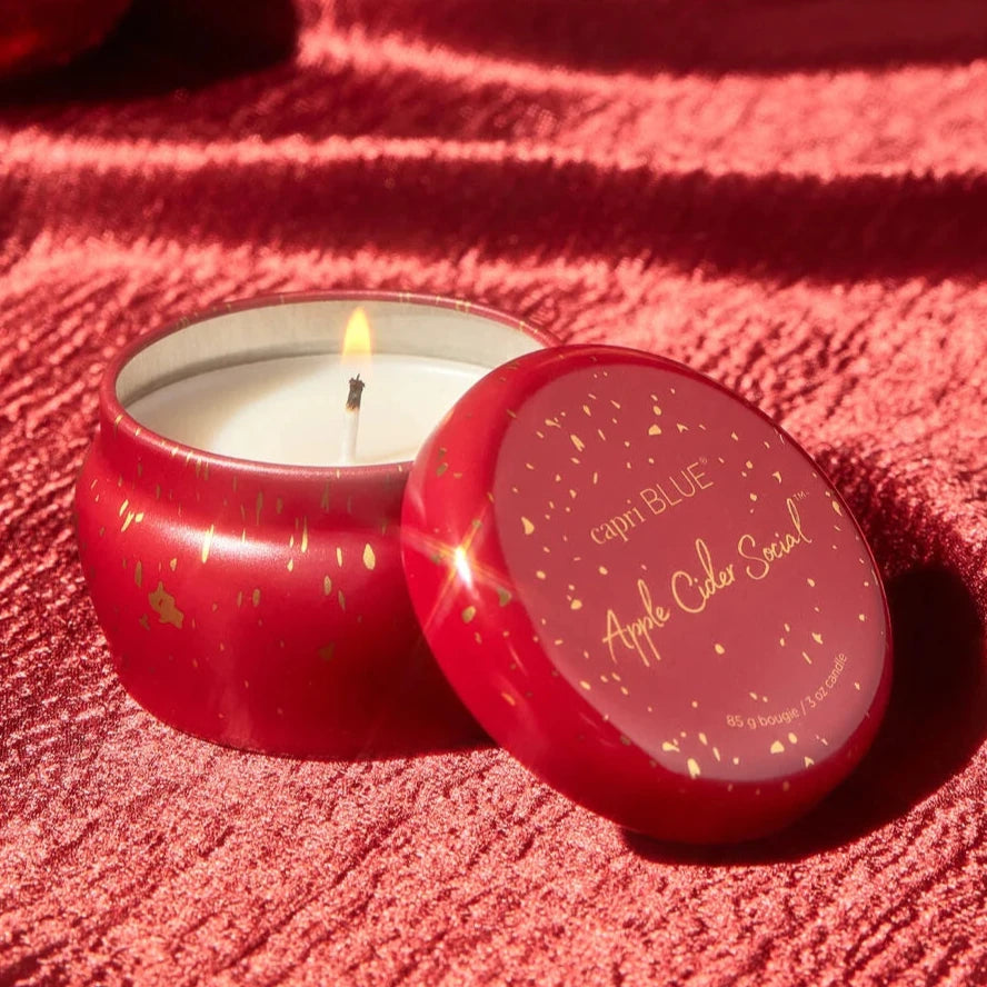 red tin candle with gold sparkles on it on a shiny red tablecloth