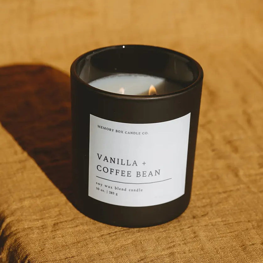 Vanilla and coffee bean candle in a black container on a textured brown surface