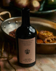 Bottle of California Harvest olive oil on a marble surface with a pan of food in the background