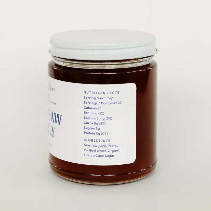 A glass jar filled with dark amber honey, featuring a white lid and a white label with blue text, set against a plain white background.