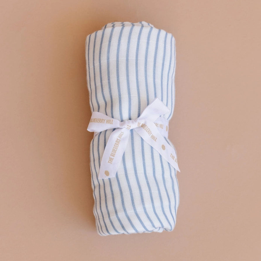Rolled-up blue and white striped fabric with a white bow on a beige background