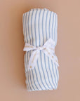 Rolled-up blue and white striped fabric with a white bow on a beige background