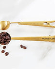 Gold coffee scoop with 'HOUSE BLEND' text and coffee beans on a white background