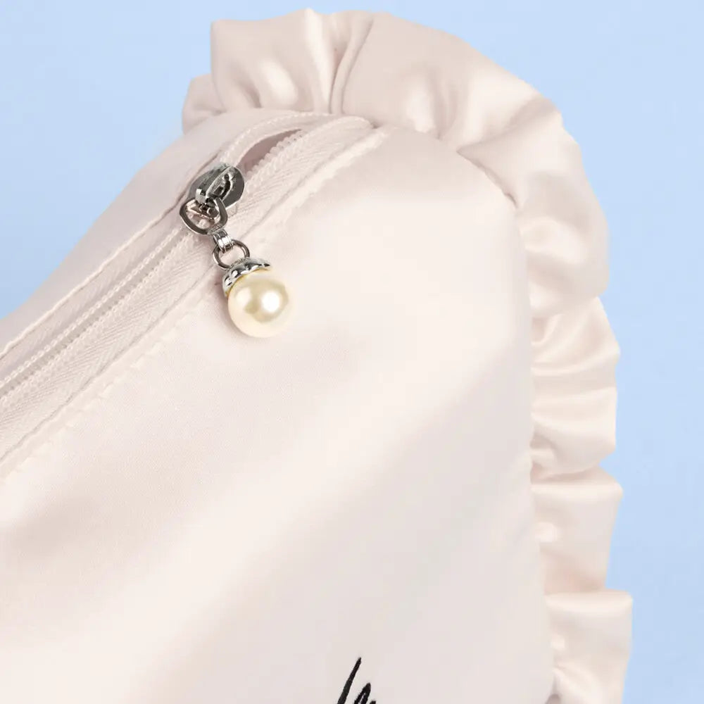 Close-up of a white garment with a pearl charm on a light blue background