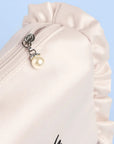 Close-up of a white garment with a pearl charm on a light blue background