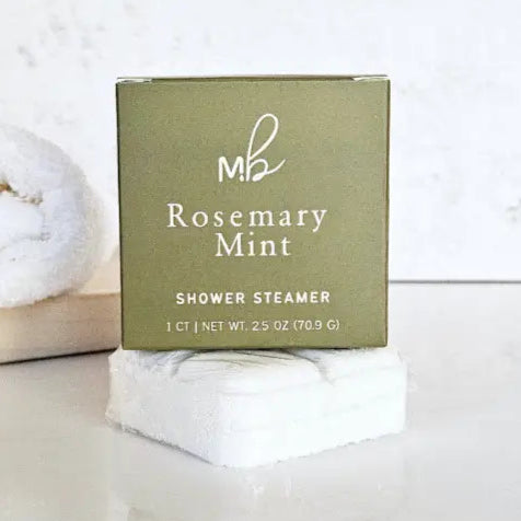 MB Rosemary Mint shower steamer on a white surface with a towel in the background