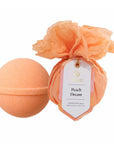 An orange peach bath bomb and matching bath topper set on a white background, with the bath topper wrapped in a paper band featuring a product tag labeled 'Peach Dream'.