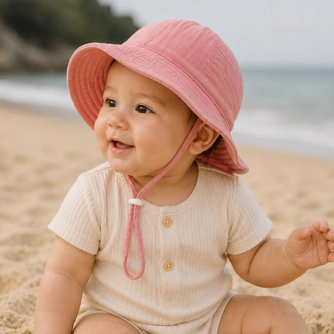 baby wearing a pink bucket hat on the beach