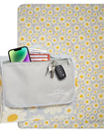 Floral-patterned outdoor blanket with a gray pocket holding a phone, cards, and keys on a white background.