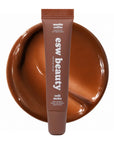 Lip treatment tube with 'esw beauty' branding on a brown plate