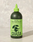 Bottle of GRAZA extra virgin olive oil on a light background