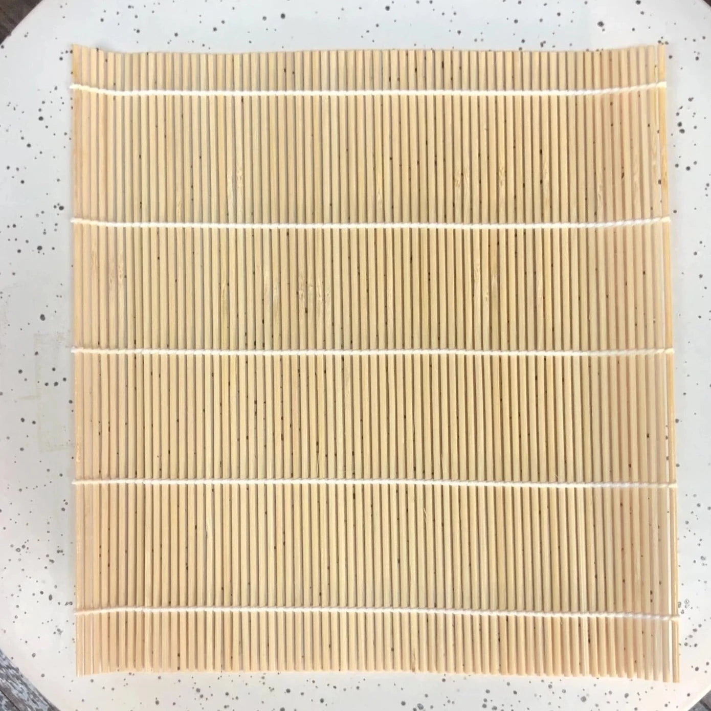 tan bamboo sushi mat on speckled plate