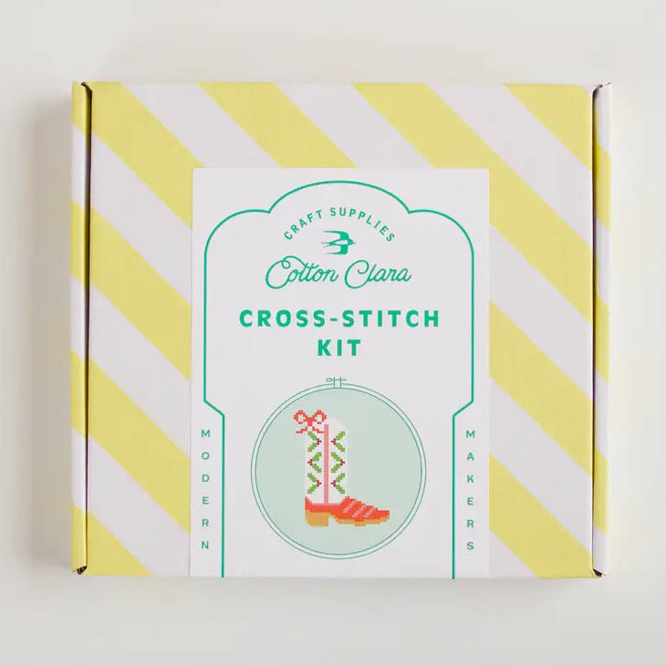 Cotton Clara cross-stitch kit packaging with yellow and white striped design on a light gray background