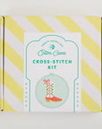 Cotton Clara cross-stitch kit packaging with yellow and white striped design on a light gray background