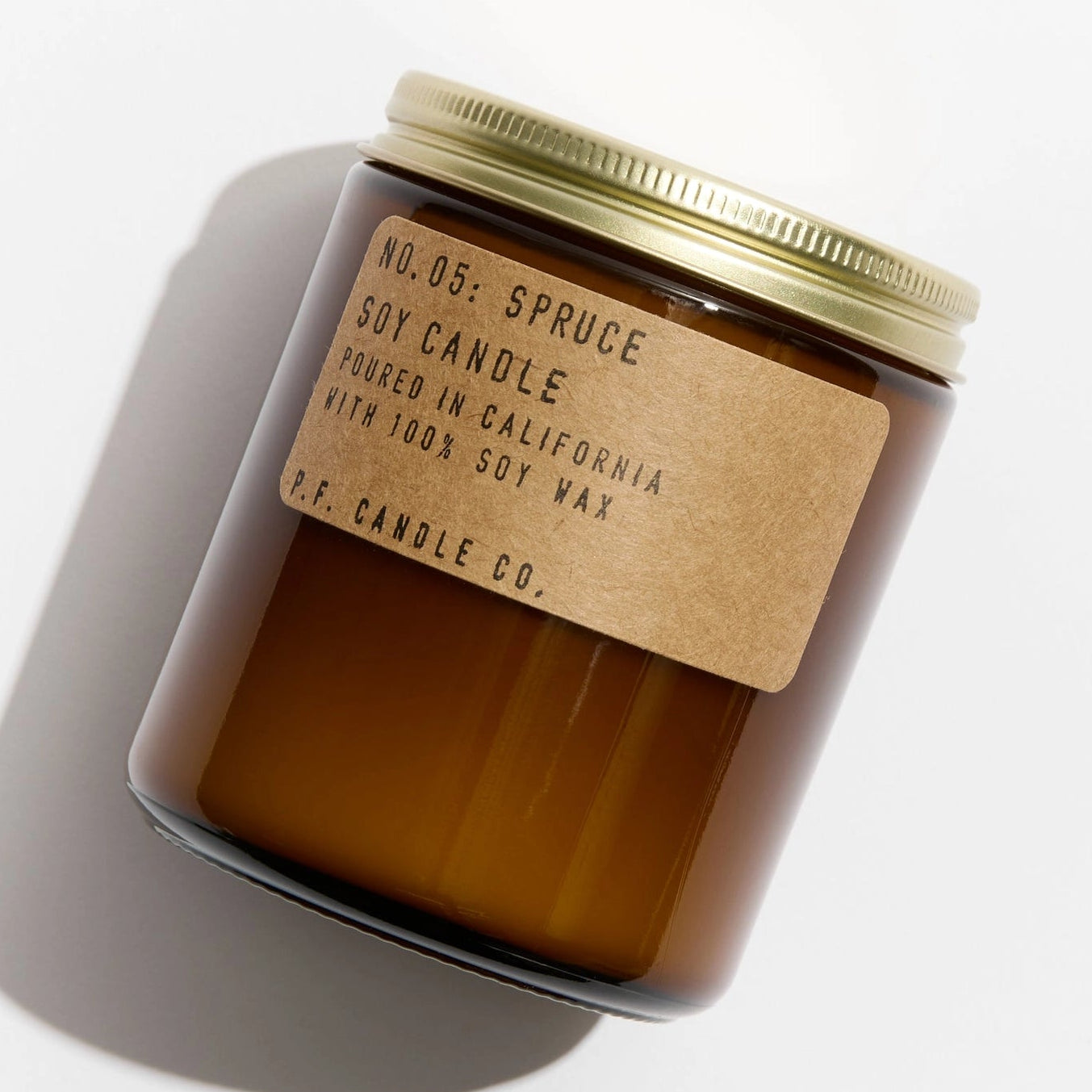 Brown candle with a gold lid and label on a white background