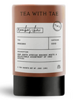 A tea sachet container labeled 'TEA WITH TAE' and 'rootbox chai', with a warm brown upper section, white label panel, and black base, shown on a light gray background.